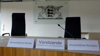 Foto zeigt eine Richterbank im Landesarbeitsgericht Baden-Württemberg und im Hintergrund das Landeswappen
